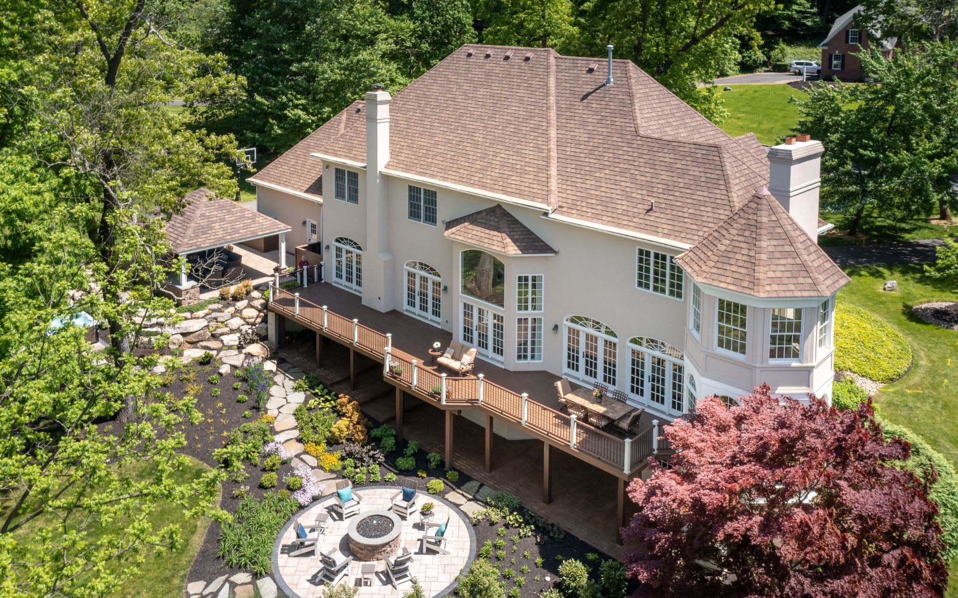 Aerial view of house with large deck and fire pit.