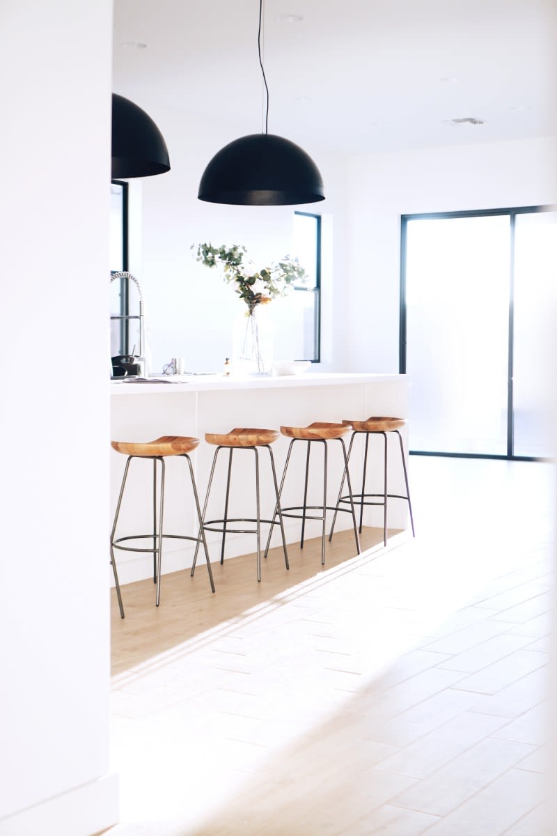  A kitchen with four bar stools and two pendant lights hanging from the ceiling