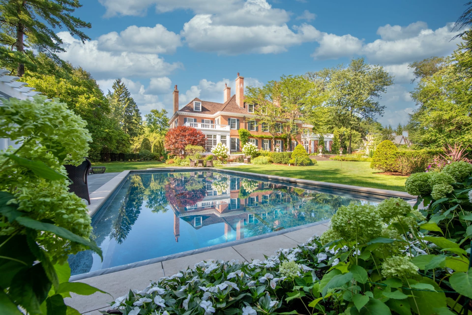 A large spacious home with a lush green yard and a swimming pool