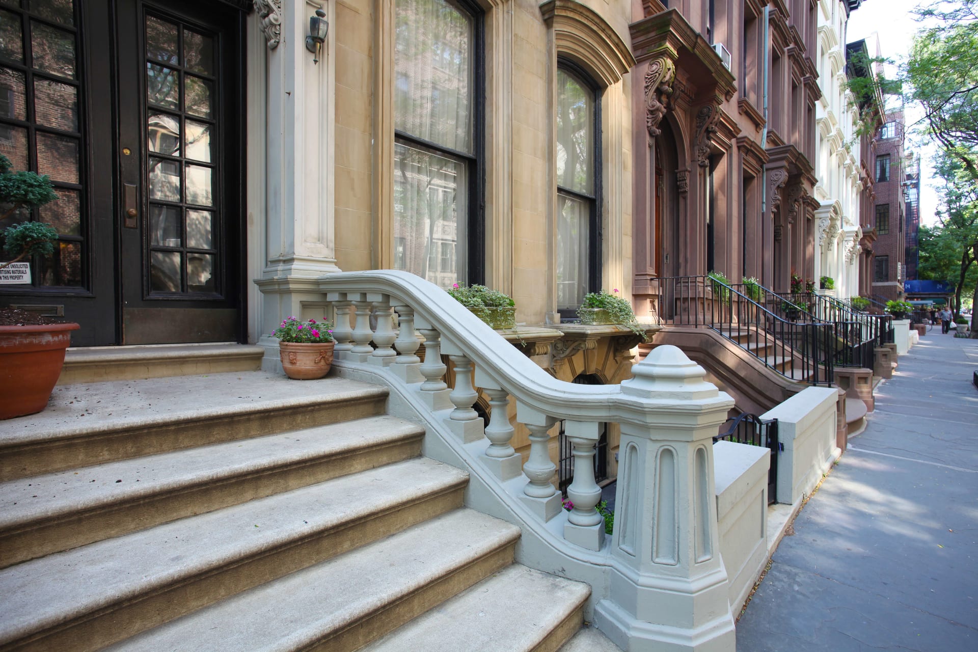 A set of stairs leading up to a brownstone building with a stone and wrought iron railing.