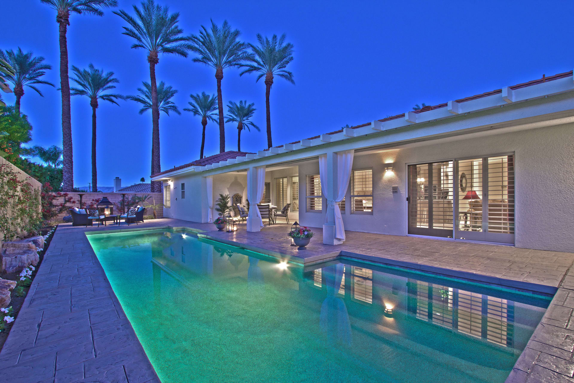 A modern house with a sparkling pool and lush palm trees