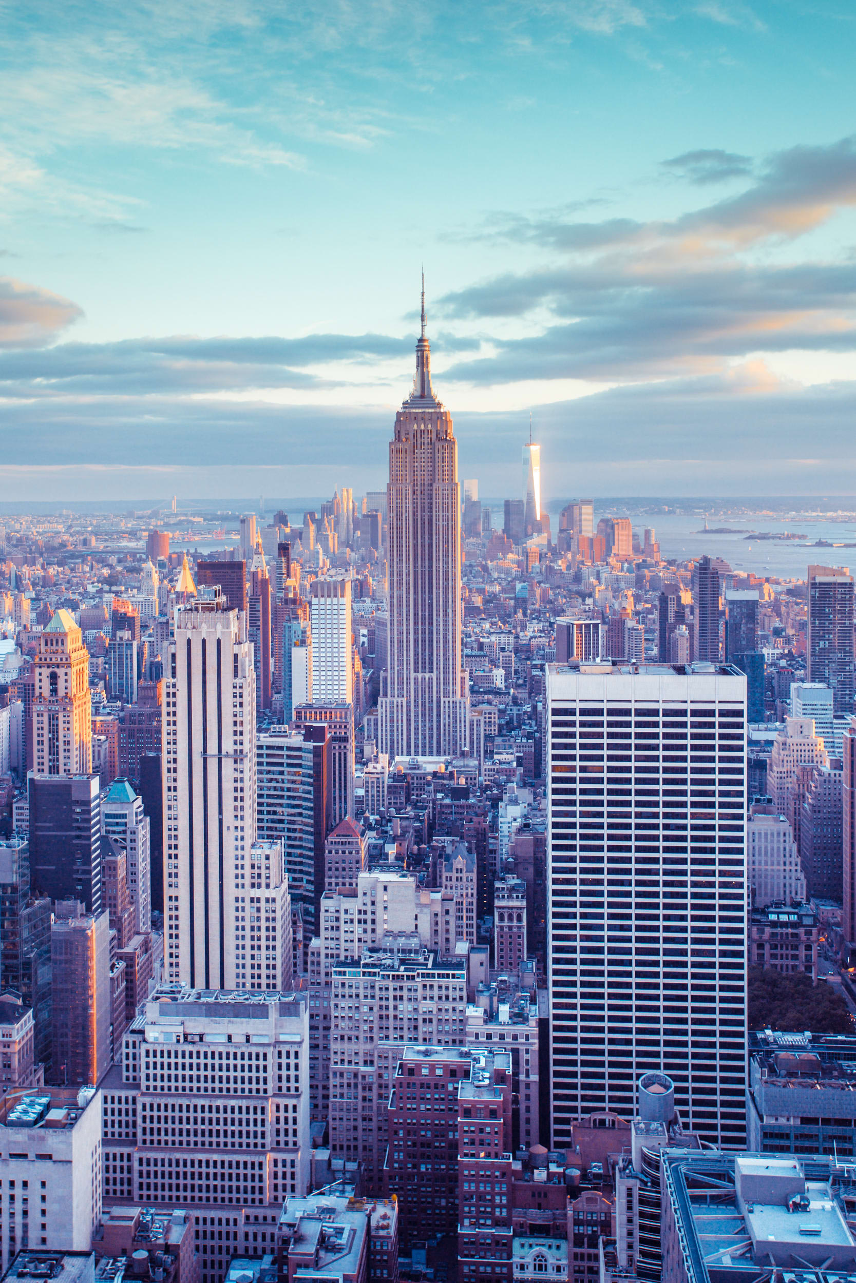 The skyline of New York City at sunset with the Empire State Building at the center.