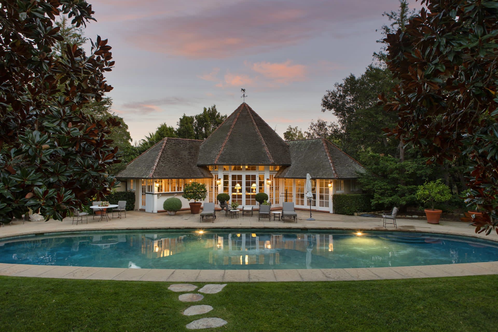 A huge house sitting next to a large pool with trees all around