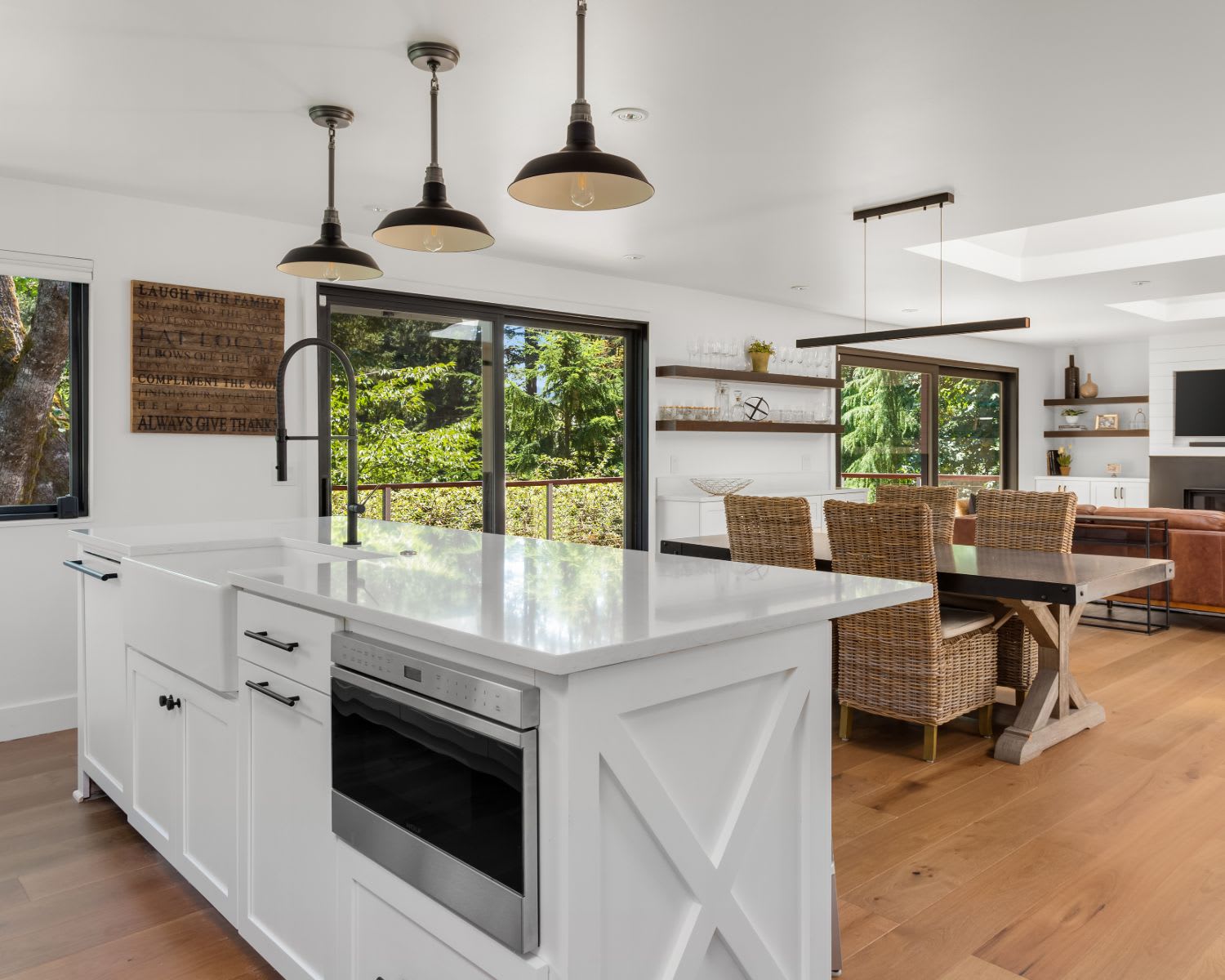 A modern kitchen with a hardwood floor, stainless steel appliances, cabinets, dining table and chairs, and pendant lights.