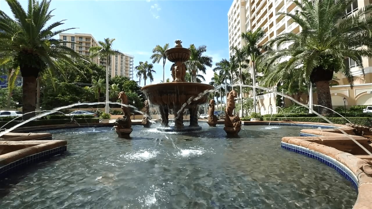 Fountain surrounded by palm trees and buildings in a city square