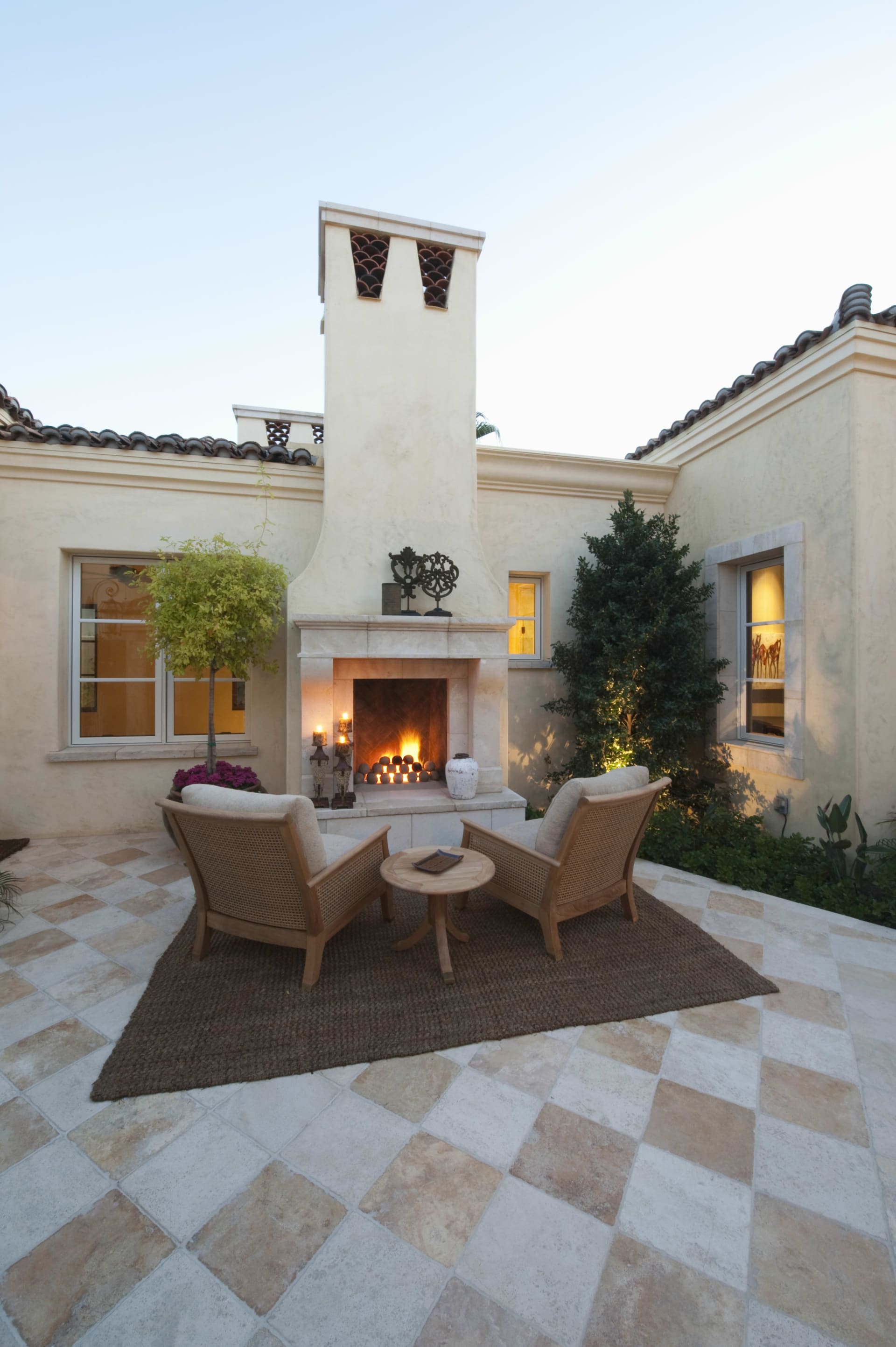 A cozy patio with two plush armchairs and a stone fireplace