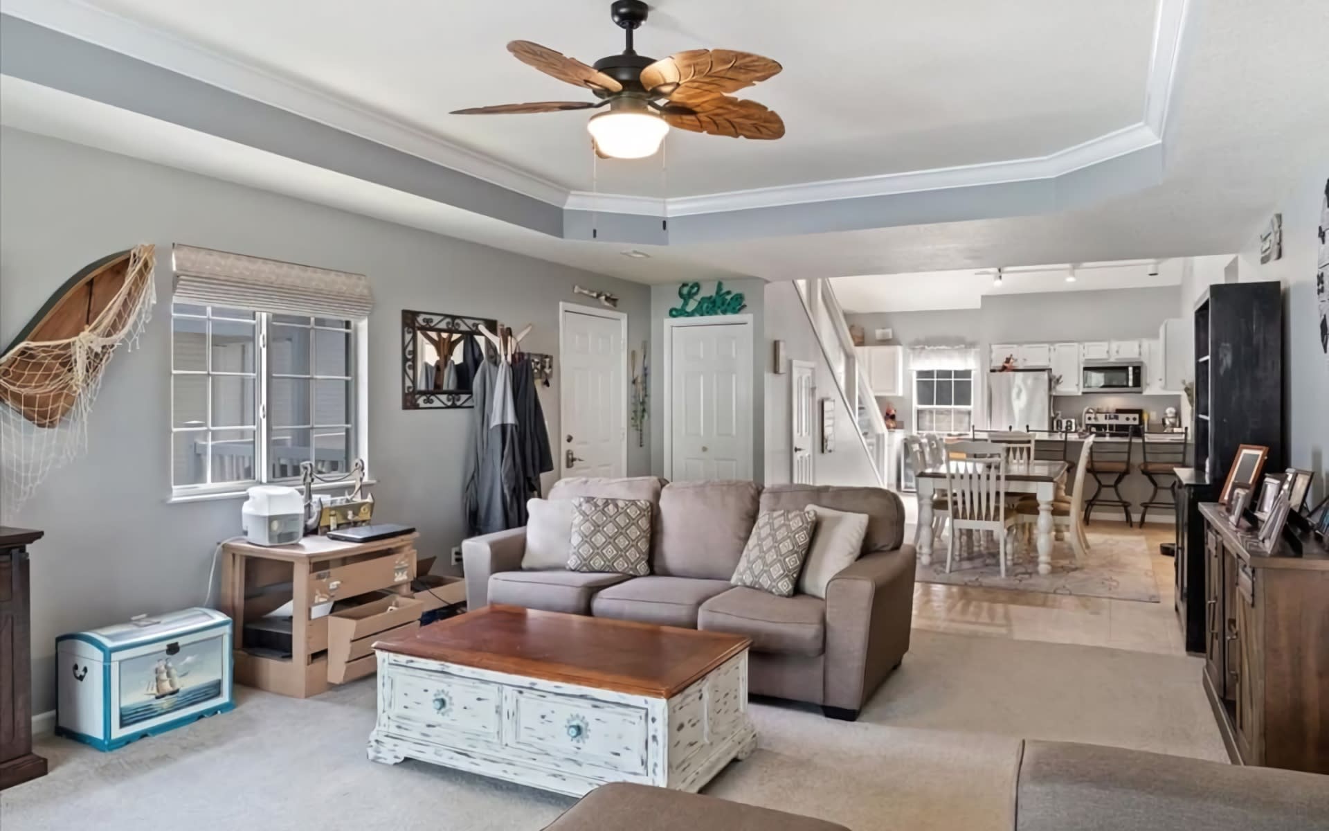 A spacious living room with gray walls and a ceiling fan