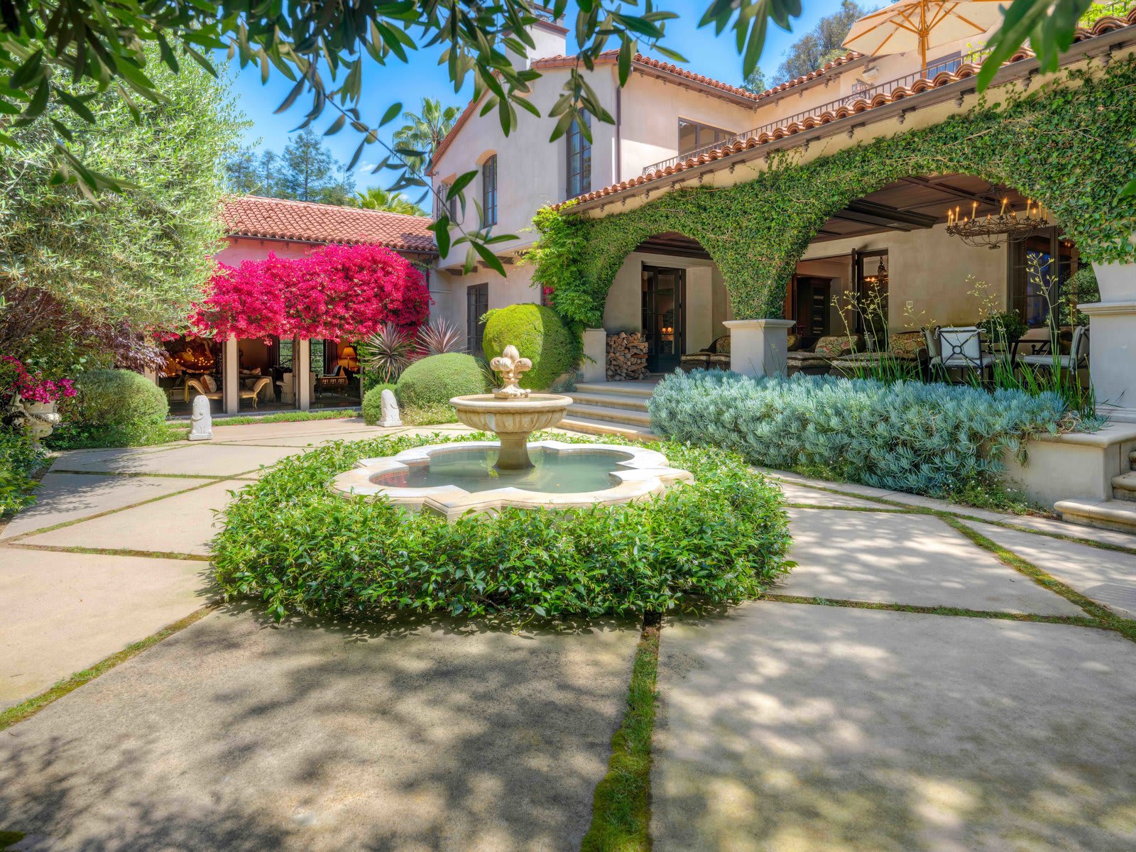 Tranquil courtyard with ornate fountain amidst colorful flowers