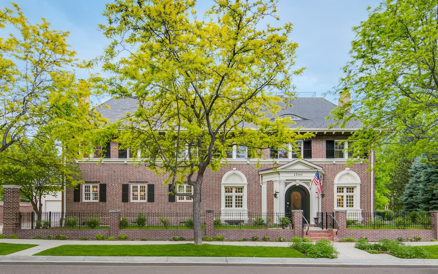 Spring day at a stately brick house with lush trees, exuding the charm and elegance of a luxury estate.